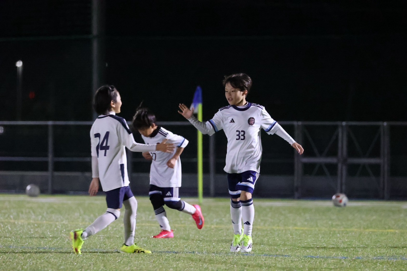 夜のピッチで仲間と手を合わせる選手たち